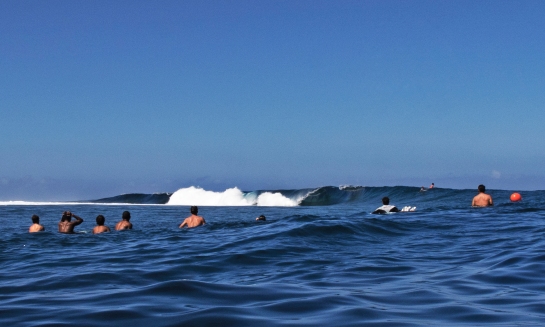 A bunch of spectators watch a heat from as close as you can get. Some waves barrel right past where these guys are chilling.